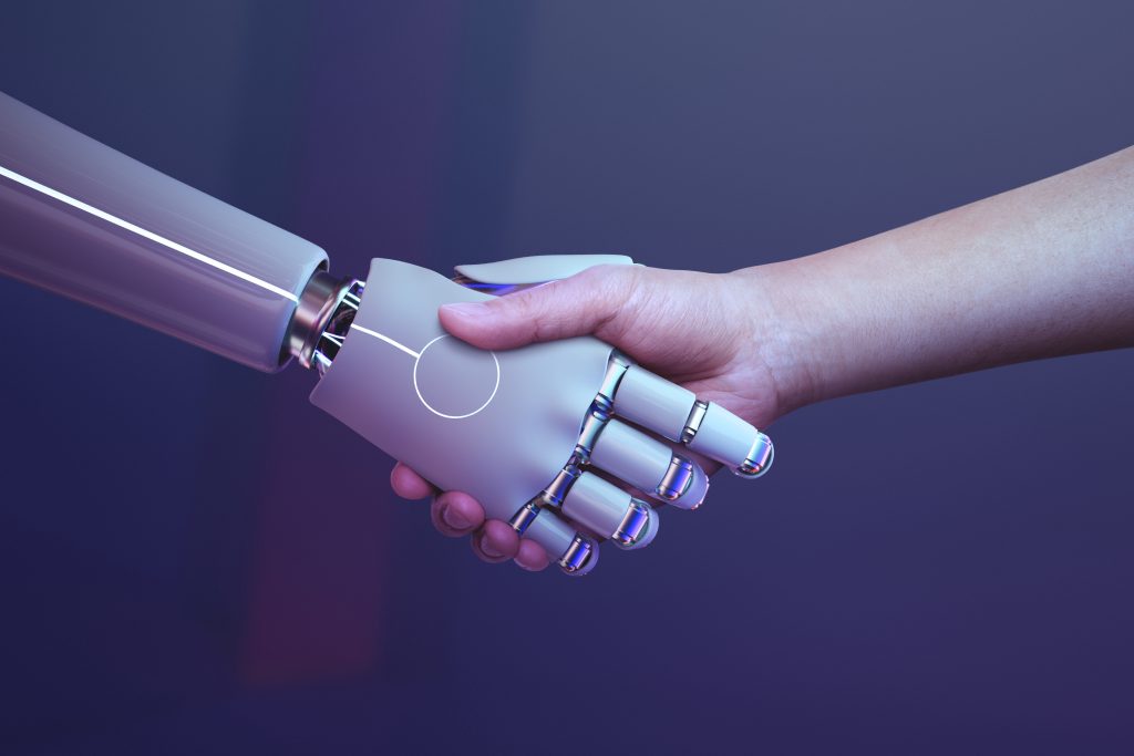 Imagem de um robô e um humano dando as mãos em sinal de acordo de negócios. 